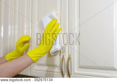 Hands In Yellow Protective Gloves Wiping Dust Off Kitchen Furniture. House Cleaning