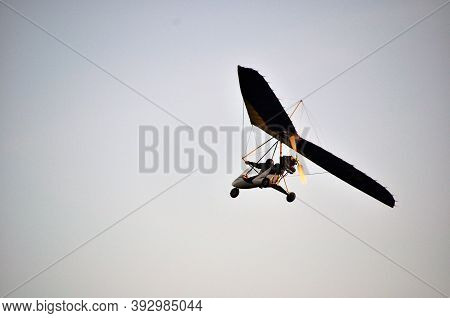 A Beautiful Motor Hang Glider Flies In The Blue Cloudless Sky Over The City