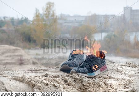 Burning Sports Sneakers Or Gym Shoes On Fire Stand On Sandy Beach Coast. Athlete Burned Out. Physica