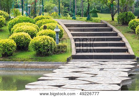 Walkway Over Lake Leading To Concrete Steps Through The Park