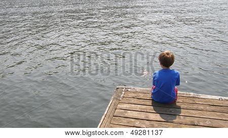 a young boy on a dock at the water's edge