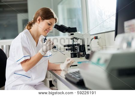 Young female researcher using pipette in medical laboratory