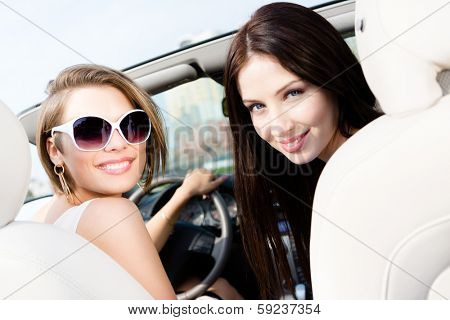 Two girls ride the car. Teenagers have a little trip on vacation