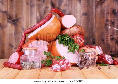 Lot of different sausages on wooden table on wooden background