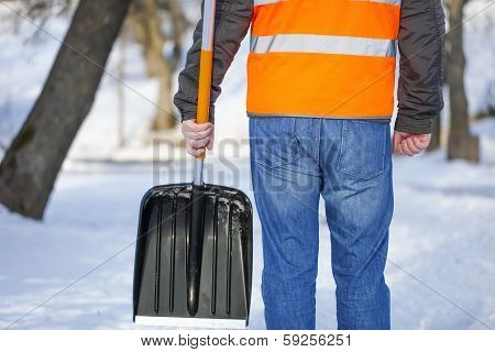 Man with a snow shovel on the sidewalk in winter