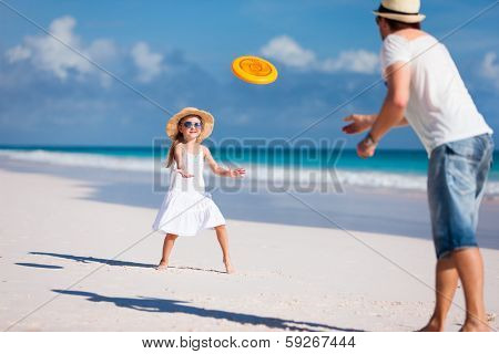 Father and daughter playing frisbee at beach