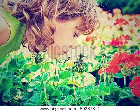 a small girl smelling some flowers done with a vintage retro instagram filter
