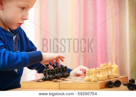Childhood. Intelligent Boy Child Kid Playing Chess. At Home.
