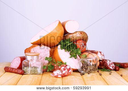 Lot of different sausages on wooden table on grey background