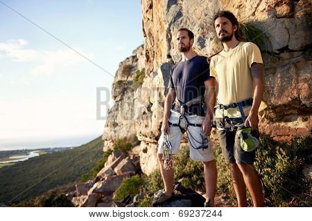 Two men looking at the view from the mountain with their rock climbing equipment on