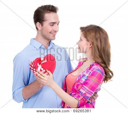 Smiling young couple with a gift in the studio looking at each other isolated on white background.