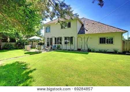 Suny Green Backyard With Yellow Hosue.