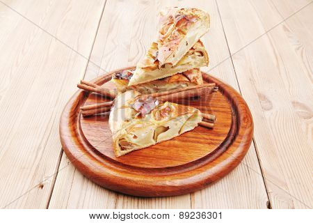 sweet food : apple pie cuts served on wooden plate over table with cinnamon sticks