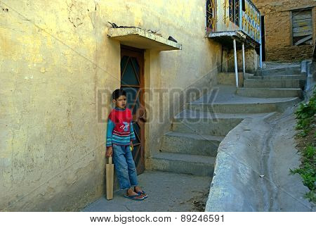 DHARAMSHALA, HIMACHAL PRADESH, INDIA -JULY 05, 2009: A teenager boy of hilly Himachal of India is waiting with a cricket bat for his friends to come and start playing at mountain steps on JULY 05, 2009 in Dharamshala, Himachal Pradesh, India. Cricket is l