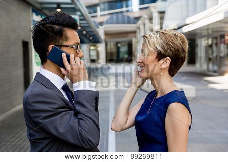 Business people standing in stret with their mobiles