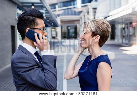 Business people standing in stret with their mobiles