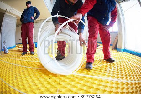 grouo of workera installing underfloor heating and colling in modern home