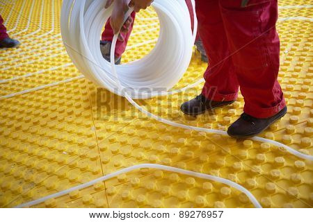 group of workers installing underfloor heating and colling in modern home