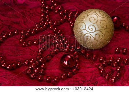 Christmas Decorations On A Red Background Accessories. Gold Ball Toy With Bright Lace.