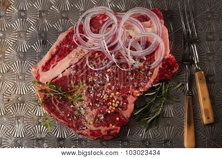 beef steak t-bone with vintage meat fork on metal backdrop