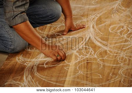 Skilled craftsman sketches carving design on wood before start carving work