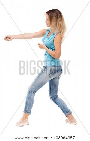back view standing girl pulling a rope from the top or cling to something. girl  watching. Rear view people collection. Isolated over white background. girl in jeans and a blue shirt pulling the rope.