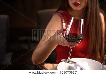 Chinese woman toasting at the restaurant with red wine and a glass