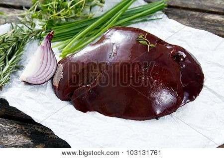 Raw Lamb Liver On Crumpled Paper, Decorated With Greens And Vegetables. On Old  Wooden Table