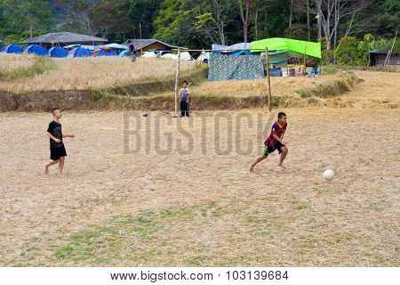 MAE KLANG LUANG, THAILAND, DECEMBER 31, 2014 : Some kids are playing soccer football in a dry harvested rice field in the village of Mae Klang Luang,  Doi Inthanon national park, Thailand