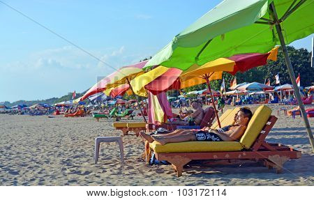Tourists Snooze On Recliner Chairs At Legian Beach, Bali