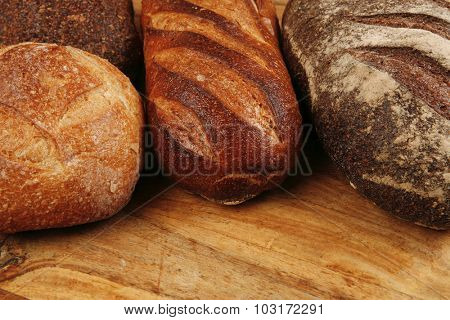 four different rye and white flour fresh french bread loaf on light wooden table