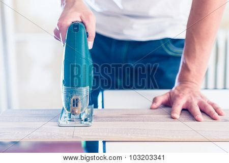 DIY worker cutting wooden panel with jig saw