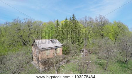 Country house among plants near forest at spring sunny day. Aerial view video frame