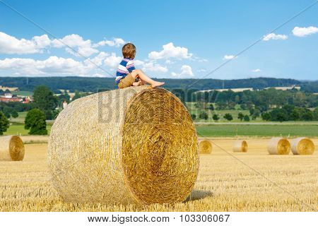 Little Kid Boy Sitting On Hay Bale In Summer