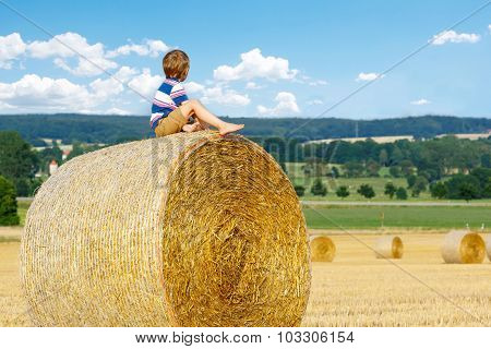 Little Kid Boy Sitting On Hay Bale In Summer