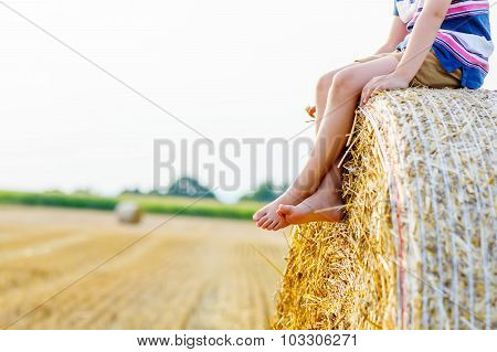 Little Kid Boy Sitting On Hay Bale In Summer
