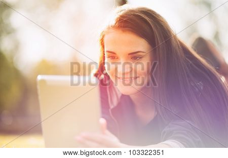 Beautiful Girl With Tablet Or Ebook Outdoor Laying On Field