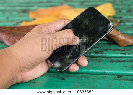 Hands holding and thump up touch on broken mobile smartphone sceen at outdoor park