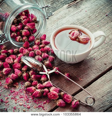 Dry Rose Flowers, Tea Cup, Strainer And Glass Jar With Rose Buds. Selective Focus. Retro Styled Phot