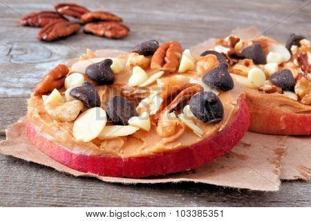 Apple rounds close up with peanut butter, chocolate and nuts