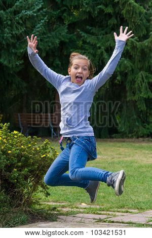 Happy child girl jumps in garden