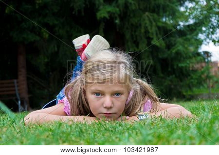 Small Blonde Girl Child With Ponytail Lay In Grass Enjoying Summer Time Alone
