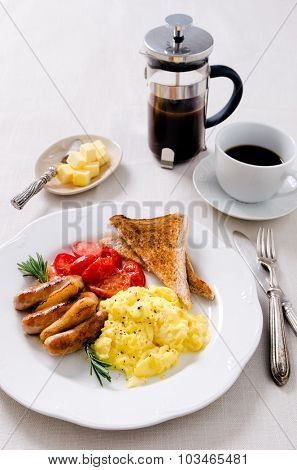 Scrambled eggs with fried tomatoes, pork sausages chipolata and wholemeal toast, full breakfast served with coffee