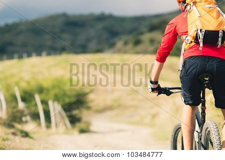 Mountain biker riding on bike in summer mountains landscape. Man cycling MTB on rural country road.
