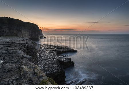 Stunning Coastal Landscape With Long Exposure Waves Crashing At Sunrise