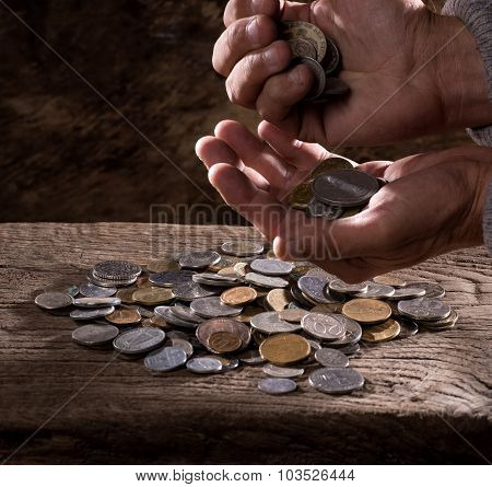 caucasian old man's hands and pile of old coins