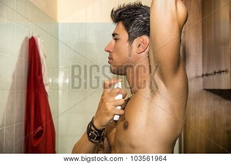 Handsome young man in bathroom, spraying cologne or perfume