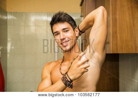 Handsome young man in bathroom, spraying cologne or perfume