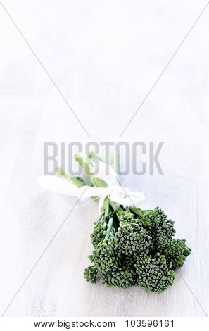 Exotic vegetable, broccolini in a bundle on rustic white background