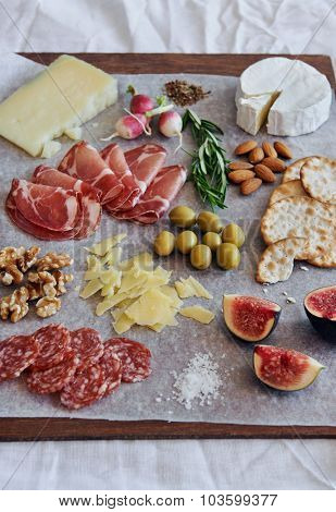 Selection of cured meat charcuterie salami, coppa, with brie camembert gruyere cheese served with olives nuts crackers and fruit